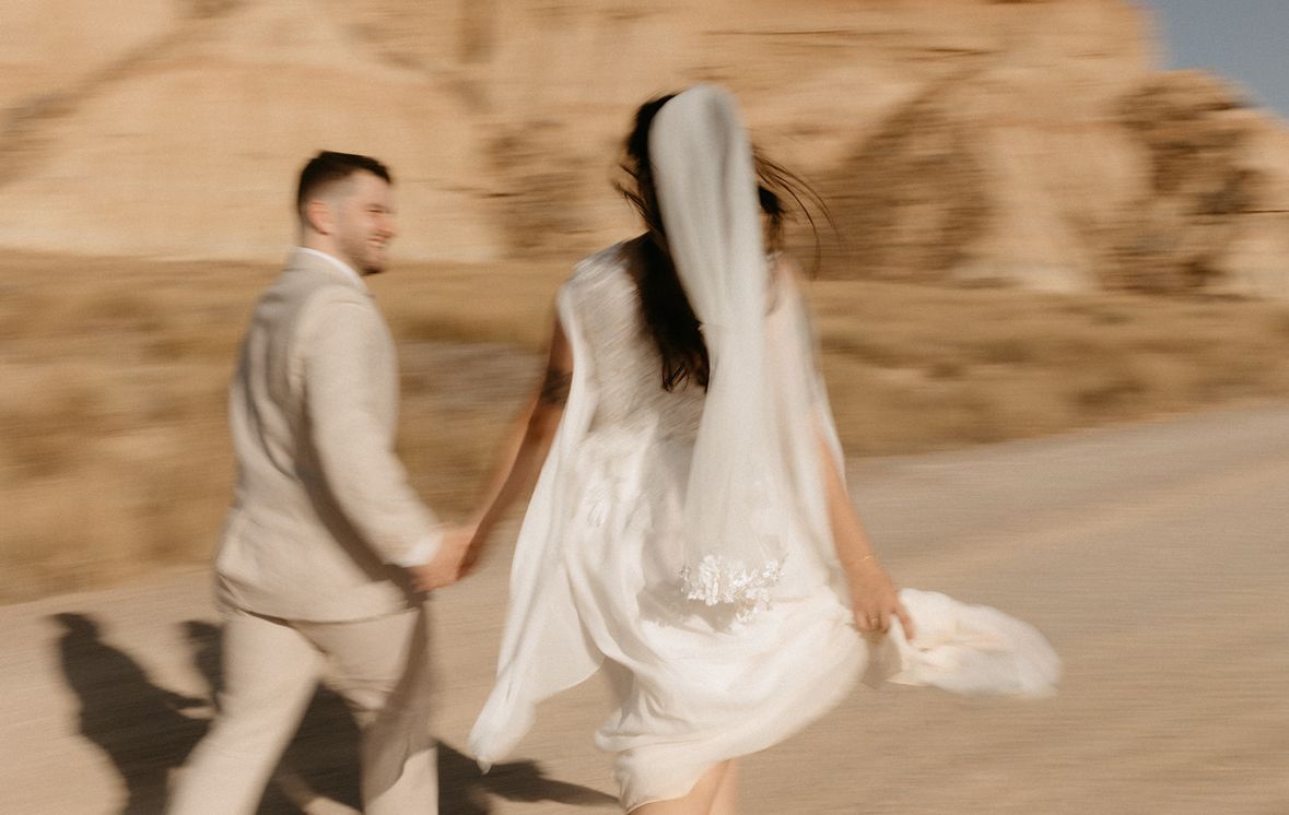 Couple de mariés courant main dans la main dans le désert des Bardenas Reales, en Espagne