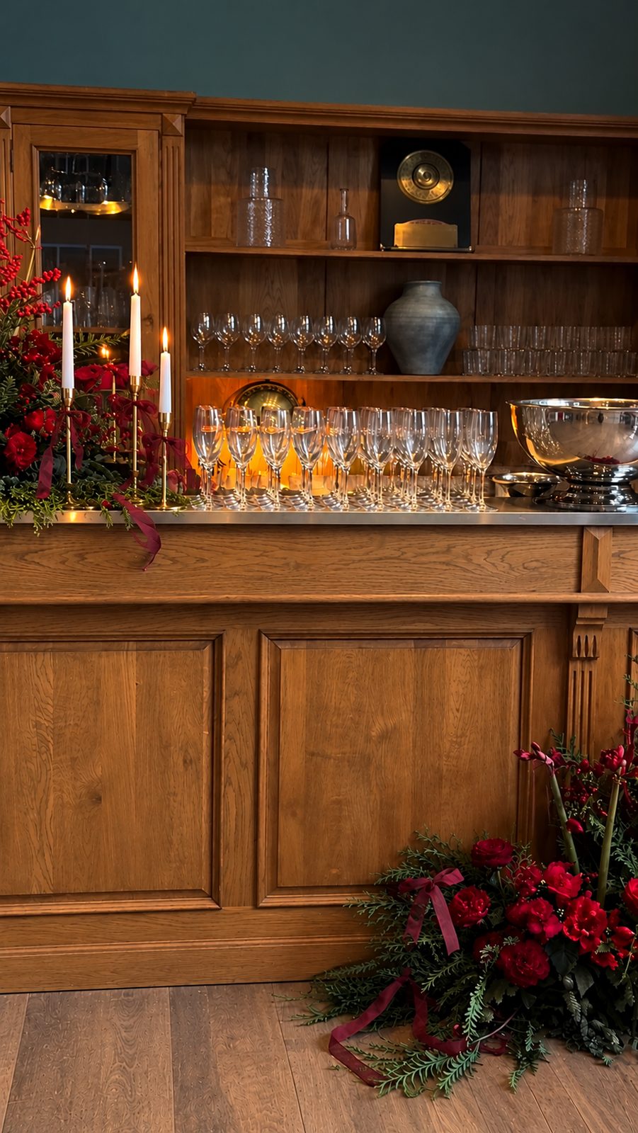 Bar en bois décoré de fleurs rouges, bougies et coupes de champagne