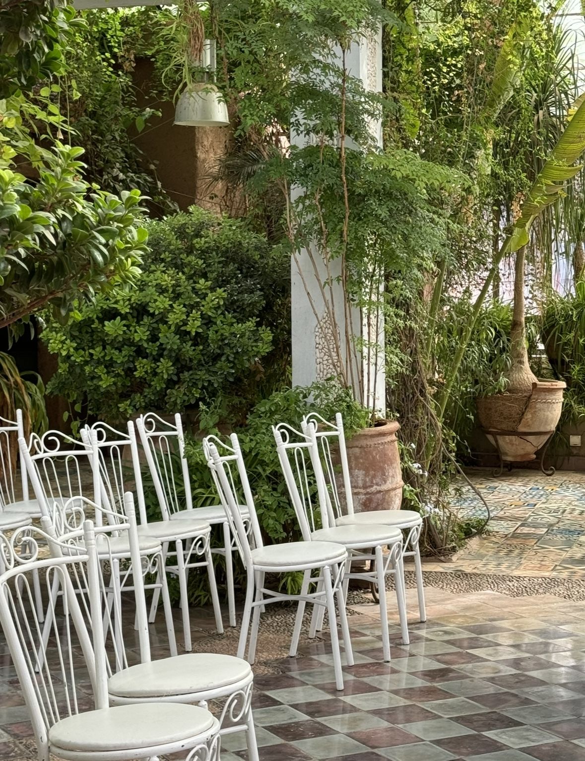 Patio verdoyant avec des chaises blanches et des carreaux de céramique