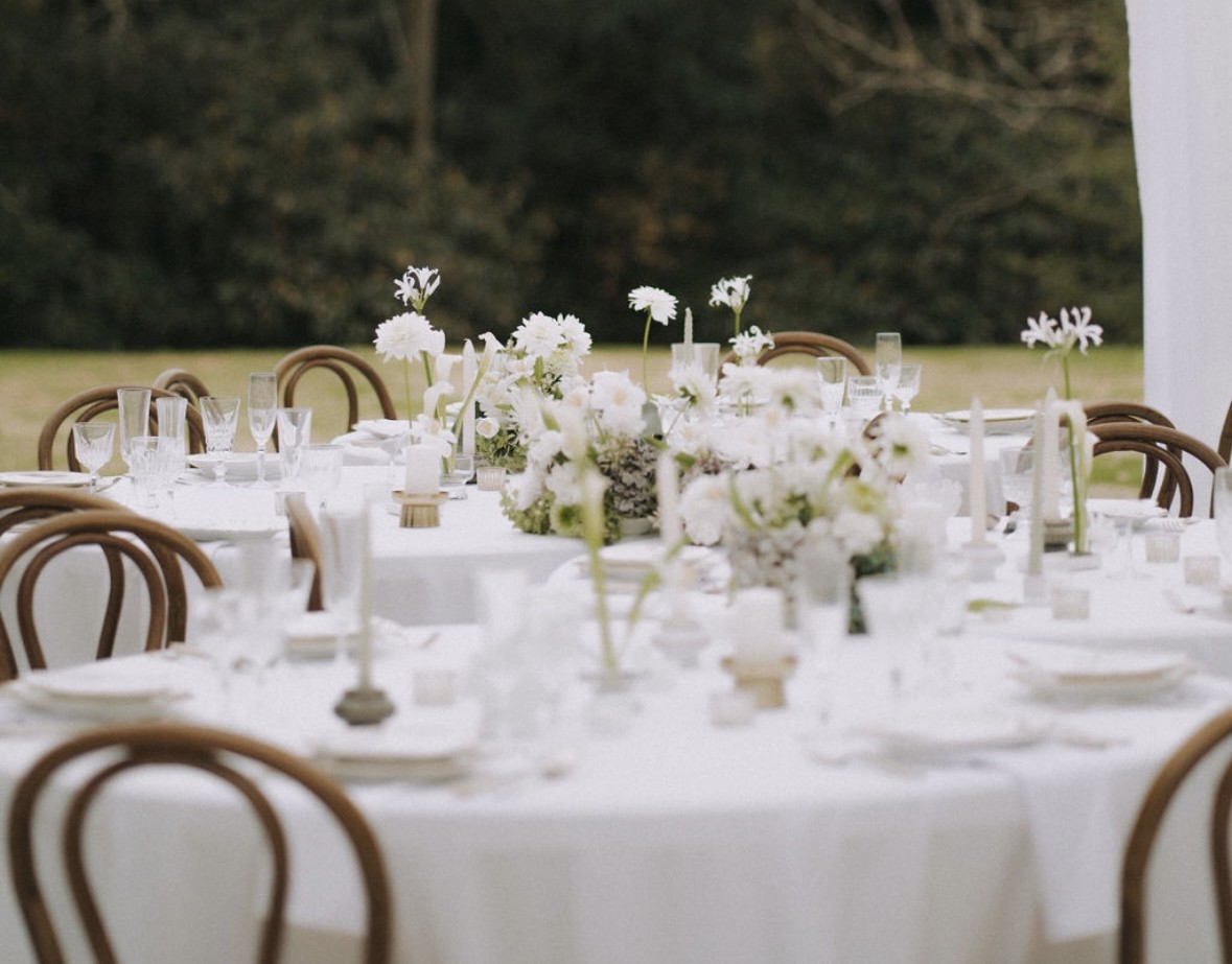 Table de mariage dressée en extérieur, nappe blanche et fleurs blanches